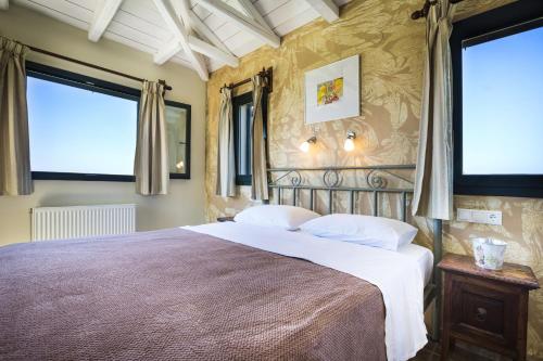 a bedroom with a large bed and two windows at Villa Haris in Argostoli