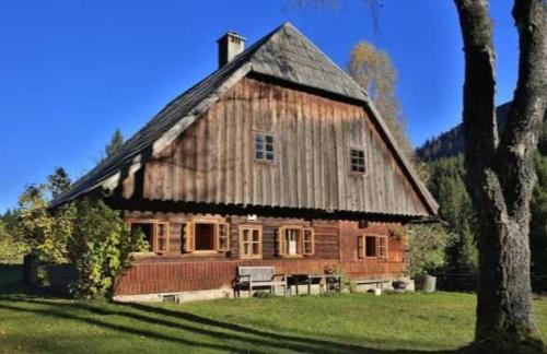 a large wooden house sitting on top of a field at Wildererhütte 240 Jahre alt 