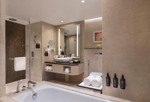 a bathroom with a bath tub and a sink at Grand Mercure Agra - An Accor Brand in Agra