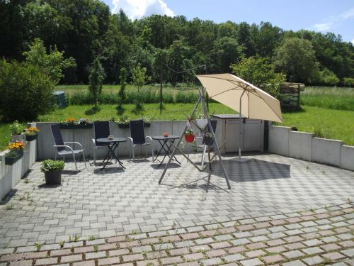 um pátio com um guarda-sol, uma mesa e cadeiras em Martini Pension Rammert em Großbettlingen