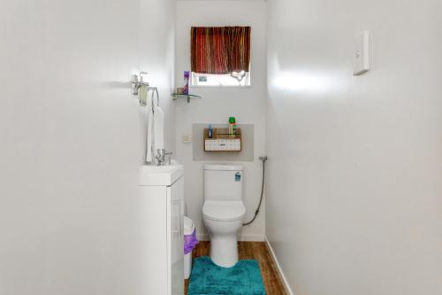 a white bathroom with a toilet and a window at Homespun Unit with deck, air-con and parking in Auckland