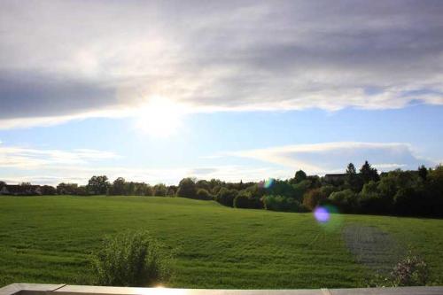 een groot groen veld met de zon in de lucht bij Ferienwohnung Wiesenweg Görlitz in Görlitz