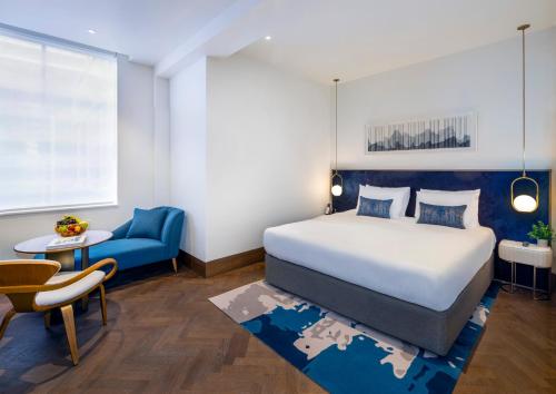 a bedroom with a large bed and a blue chair at Dao by Dorsett North London in London