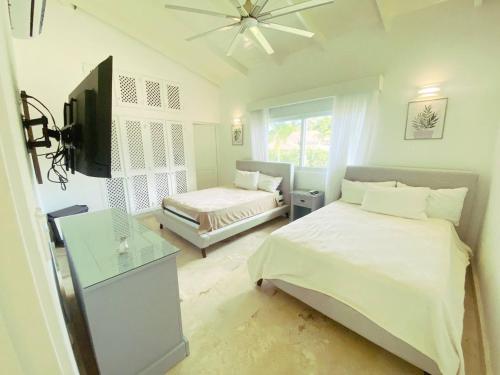 ein Schlafzimmer mit einem Bett und einem TV in der Unterkunft Seasideserenity Luxury Villa Steps From The Beach in La Romana