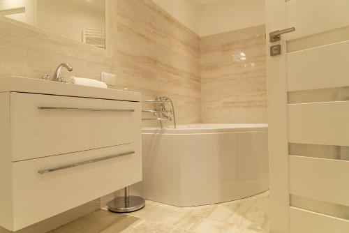 a white bathroom with a tub and a sink at VacationClub - Ochorowicza 3E VacationHome in Wisła