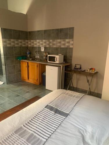 a room with a kitchen with a bed and a microwave at MAM in Mokopane