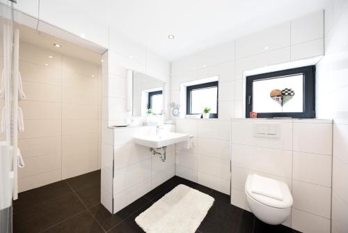 a white bathroom with a sink and a toilet at Hotel Restaurant Sengscheider Hof in Sankt Ingbert