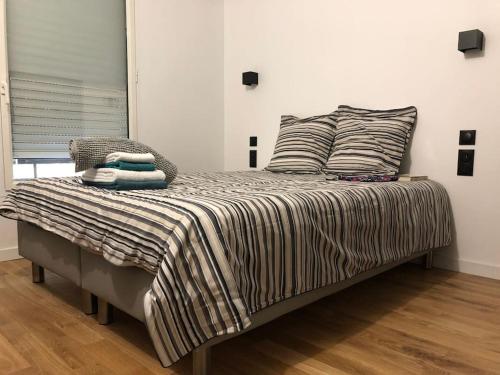 - un lit avec des oreillers et une couverture rayée dans l'établissement 2 pièces calme sur jardin, Centre Ville, à Boulogne-Billancourt