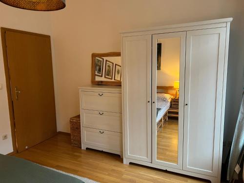 a white cabinet with a mirror and a bedroom at BELIEBT Zentrales & ruhiges Innenstadtapartment in Halle an der Saale