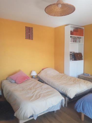 2 camas en una habitación con paredes amarillas en Le Puech et vous en Saint-André-de-Majencoules