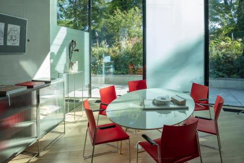 uma sala de jantar com uma mesa de vidro e cadeiras vermelhas em Ola Foundation Residence em Riga