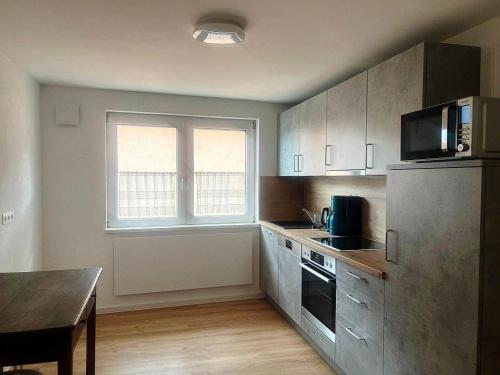 eine Küche mit einem Kühlschrank, einem Tisch und einem Fenster in der Unterkunft Eisvogel-Apartment in Rust in Rust
