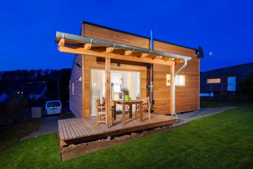 Cabaña de madera pequeña con mesa en la cubierta en Ferienhaus Eifeltraum Magma en Berlingen