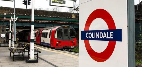 a train pulling into a train station with a sign at Stunning 2-Bed Apartment near Colindale Station in Hendon