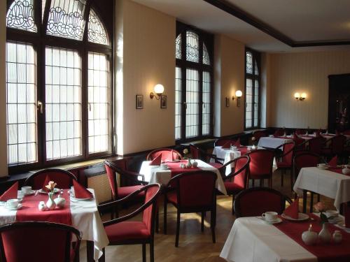 un comedor con mesas, sillas rojas y ventanas en Hotel Marthahaus, en Halle an der Saale