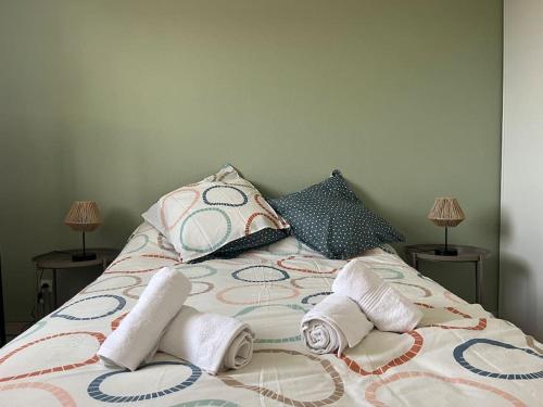 a bed with three pillows and towels on it at Appartement lumineux terrasse piscine in Cugnaux