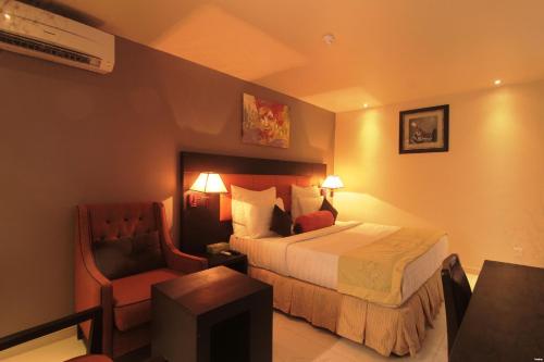 a hotel room with a bed and a chair at Oakspring Hotel and Luxury Suites in Lagos