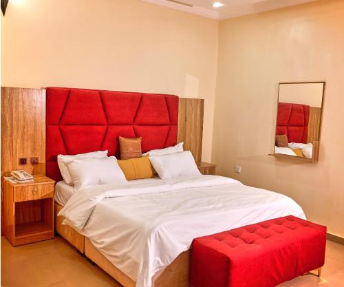 a bedroom with a large bed with a red headboard at Bosanic Hotel in Benin City