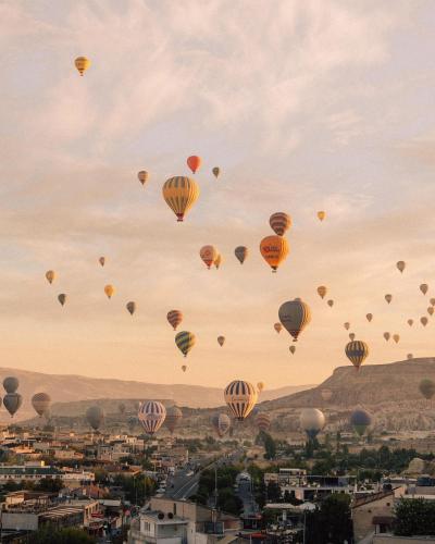 a bunch of hot air balloons flying over a city at Cappadocia Cave Suites Adult Only in Goreme