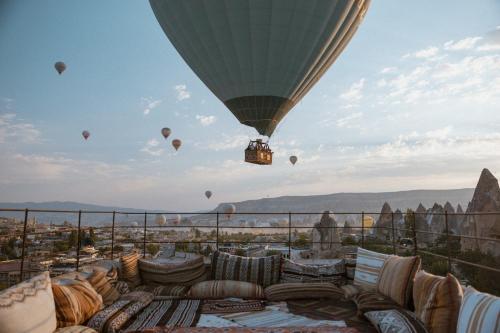 a hot air balloon flying in the sky with couches and balloons at Cappadocia Cave Suites Adult Only in Goreme
