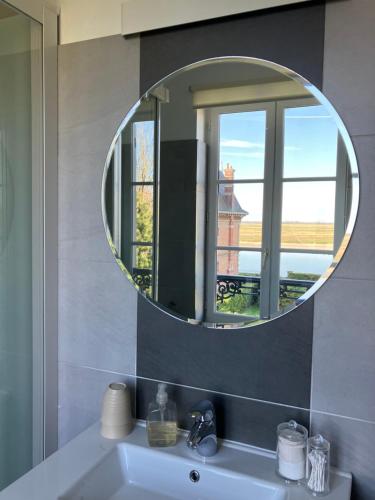 a bathroom with a mirror over a sink with a window at Chambres avec Vue in Saint-Valery-sur-Somme