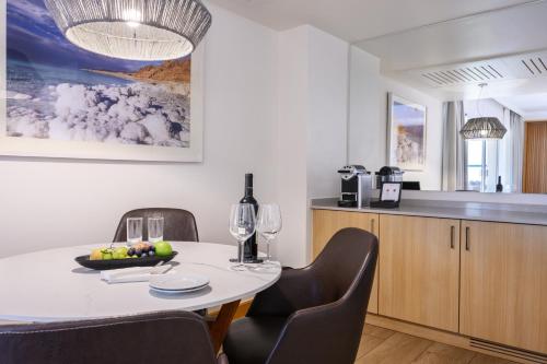a dining room with a table and chairs and a kitchen at Nevo by Isrotel Collection in Ein Bokek