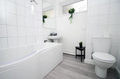 a white bathroom with a tub and a toilet at Peaceful 3 Bed Flat with Parking and Balcony by CTO Serviced Apartments in Cardiff
