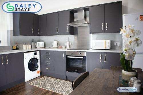 a kitchen with black cabinets and a washer and dryer at Manchester Apartment with Free Gated Parking by Daley Stays in Manchester