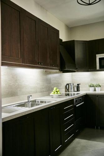 a kitchen with dark wooden cabinets and a sink at Palacina The Residence & The Suites in Nairobi