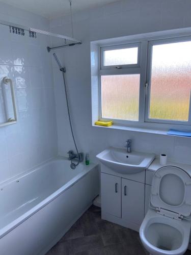 a bathroom with a tub and a toilet and a sink at 14 Wallcourt Road in Biddenham