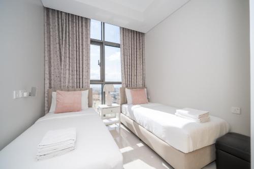 two beds in a room with a window at ALH Vacay - Aykon City 2 Tower C - 2 bedrooms in Dubai