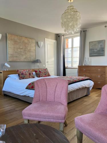 a bedroom with a bed with pink chairs and a chandelier at Chambres avec Vue in Saint-Valéry-sur-Somme