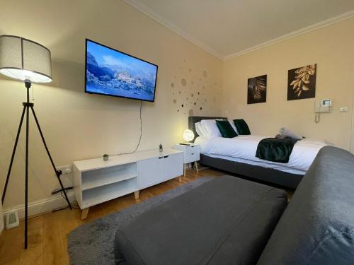 倫敦的住宿－The Islington Hub，一间卧室设有两张床,墙上配有电视。
