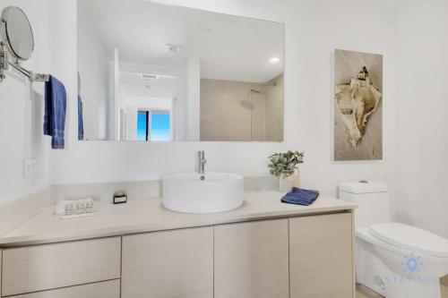 a white bathroom with a sink and a toilet at Infinite Views, Amazing Pool, Gym, Near Beach in Hallandale Beach