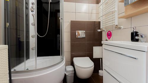 a bathroom with a shower and a toilet and a sink at VacationClub - Planeta Apartament 112 in Mielno