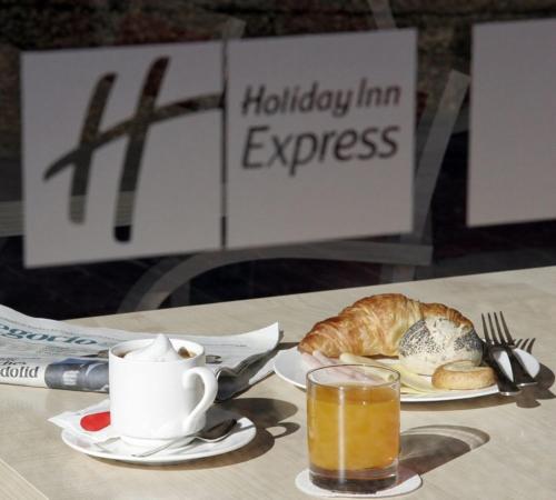 a table with a cup of coffee and a plate of bread at Hotel Holiday Inn Express Madrid-Rivas by IHG in Rivas-Vaciamadrid