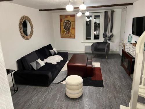 un salon avec un canapé noir et une table dans l'établissement Ndiam 's, à Honfleur