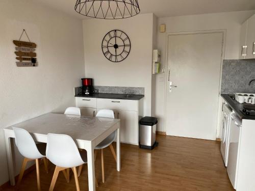 una cucina con tavolo e sedie bianche in una stanza di T2, accès direct plage, proche thalasso a Cabourg