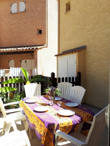 een tafel met witte stoelen en een paars tafelkleed bij Pavillon Duplex T2/terrasse in Cap d'Agde