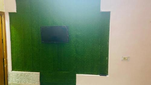 a green wall with a tv in a room at Inpalace guest house in Gwalior
