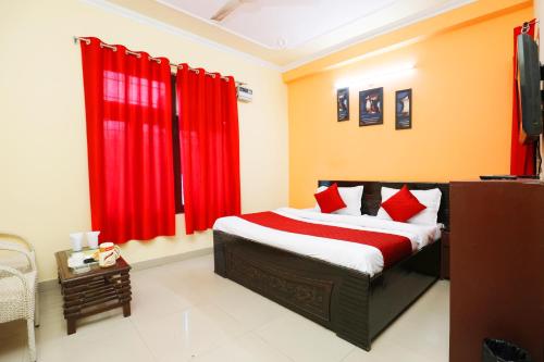 a bedroom with a bed with red curtains and a television at Hotel Sunlight Inn in New Delhi