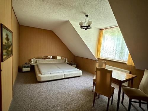 オルシュティネクにあるLeśna Chataのベッドルーム1室(ベッド1台、テーブル、窓付)