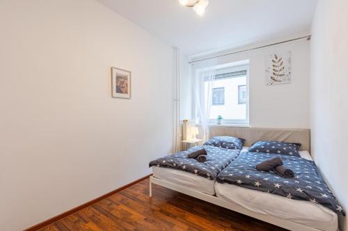- une chambre avec un lit doté de draps bleus et une fenêtre dans l'établissement CitySerenity Rustic Apartment, à Bratislava