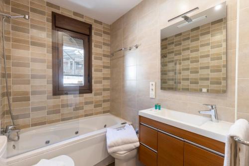 a bathroom with a tub and a sink and a mirror at BiBo Suites Sierra Nevada in Sierra Nevada