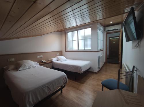 a small room with two beds and a tv at Hotel Hórreo by Bossh! Hotels in Santiago de Compostela