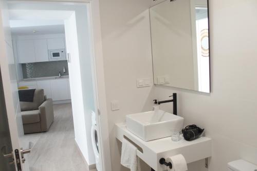 W białej łazience znajduje się umywalka i lustro. w obiekcie Torre Solana 41 w Kadyksie