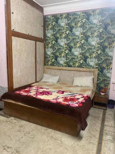 a bed in a room with a wall with a mural at Inpalace guest house in Gwalior