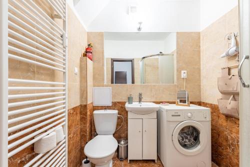 a bathroom with a toilet sink and a washing machine at CitySerenity Rustic Apartment in Bratislava