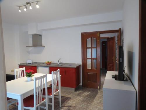 a kitchen with a white table and a red cabinet at Apartamentos Turisticos Ca Ramon in Beniarrés