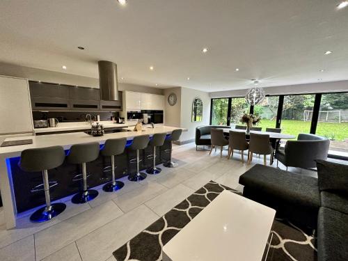 a kitchen and living room with a bar and chairs at Luxury 5 Bed all en-suite home with Hot tub in Hale